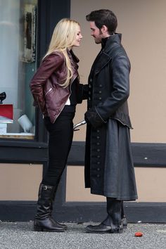 a man and woman standing next to each other in front of a storefront window