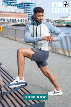 a man in grey shorts and white hoodie is doing squat exercises on a bench