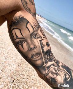 a man with a clock on his arm next to the ocean and beach is covered in tattoos