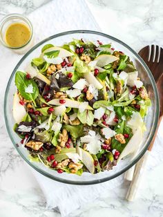 a salad with apples, walnuts and pomegranate in a glass bowl