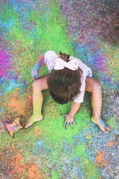 a woman laying on the ground covered in colored chalk and holding her hands up to her chest