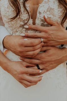 the bride and groom are holding each other's hands while they hold their wedding rings