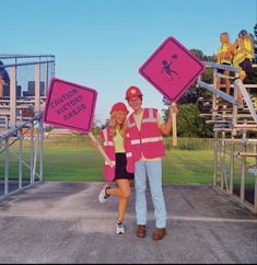 a man and woman holding up pink signs