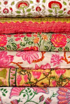 a stack of colorful fabrics with flowers on them, all in different colors and patterns