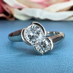 two diamond rings sitting on top of a blue surface with flowers in the background,