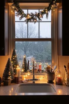 a kitchen sink under a window decorated with christmas lights and garlands on the windowsill