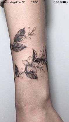 a woman's arm with flowers and leaves on it