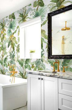 the bathroom is decorated with tropical wallpaper and gold faucets, along with a claw foot tub