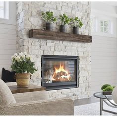 a living room with a fire place in the center and flowers on the fireplace mantel