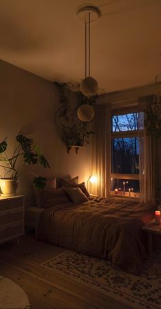 a bed room with a neatly made bed next to a window and some plants on the wall