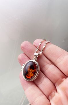 We are obsessed with vintage lockets! And this one is amazing! Fiery amber set in silver, this locket opens and can hold two pictures, or something tiny you would like to hold close to your heart. This necklace looks great on and catches the light beautifully. Pendant measures 1.25"x.85". Twist chain measures 20" long. Amber Pendant Locket Jewelry, Amber Locket Jewelry As A Gift, Amber Locket Jewelry For Gift, Locket Necklace Vintage, Silver Locket Necklace, Silver Locket, Vintage Lockets, Natural Amber, Silver Lockets