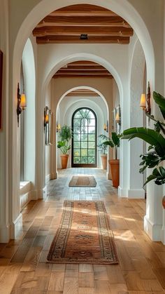 an arched hallway with wooden floors and potted plants on either side of the doorway