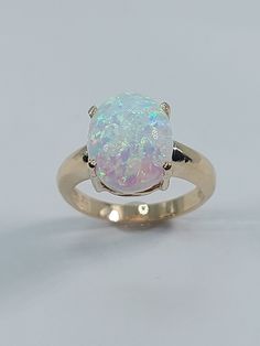 This stunning Lab Opal ring has been carefully crafted in 10k Yellow Gold, Synthetic Opal Stone . Great for any occasion! Buy it for your-self or for someone you love! This beautiful ring will not go unnoticed. All of my jewelry is handmade from scratch and of high quality.  Ring is size 6 1/2 but can be resized at no extra cost and will be shipped to you in an elegant gift box. A tracking shipping number will be provided to you once ring has been mailed. Ring Weight: 4.0 grams Stone Measurement Anniversary Opal Ring Stamped 14k In Oval Shape, Oval Opal Ring Stamped 14k For Anniversary, Yellow Gold Solitaire Opal Ring For Anniversary, 14k Gold Opal Ring Hallmarked, White Opal Ring Stamped 14k For Gift, White Opal Ring Stamped 14k As Gift, Classic Opal Jewelry For Anniversary, Hallmarked Round Cut Opal Ring For Anniversary, 14k White Gold Opal Ring For Anniversary