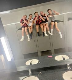 four girls hanging upside down in a public restroom