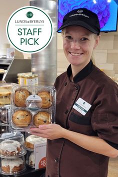 a woman holding up a tray of doughnuts in front of a sign that says staff pick