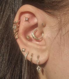 a woman wearing multiple ear piercings with stars and moon designs on her left ear