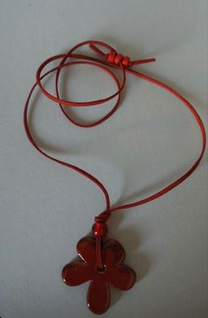 a red cord with a flower shaped pendant hanging from it's end on a white surface