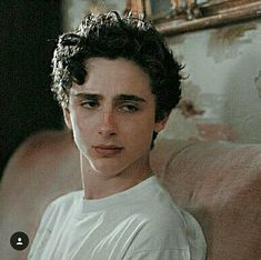 a young man with curly hair sitting on a couch