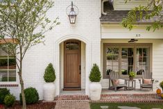 a white house with two large planters in front of it and a wooden door