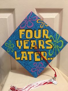 a blue graduation cap with four years later written on it and a tassel hanging from the front