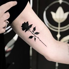 a woman's arm with a black rose tattoo on it