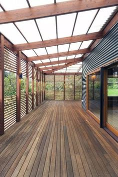 an outdoor covered deck with sliding glass doors and wood slats on the side wall