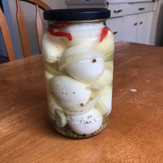 a jar filled with pickled onions on top of a wooden table