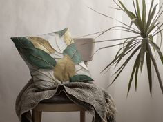 a chair with a pillow on it next to a potted plant