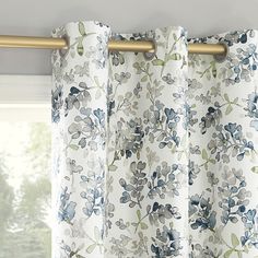 the curtains are hanging in front of a window with flowers on them and gold hardware