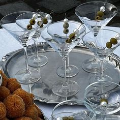 there are many glasses with olives in them on the tray next to each other