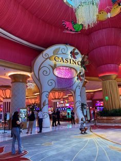 people are standing in front of a casino sign and chandelier hanging from the ceiling