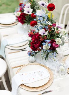 the table is set with plates and flowers in vases on top of each plate