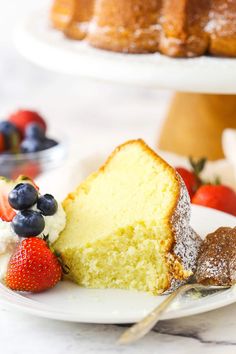 a piece of cake on a plate with berries and powdered sugar next to it