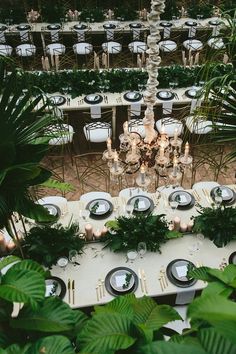 the table is set for an event with white linens and greenery on it