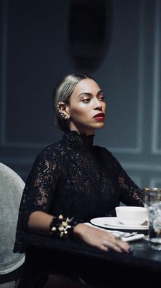 a woman sitting at a table with a glass of red wine in front of her