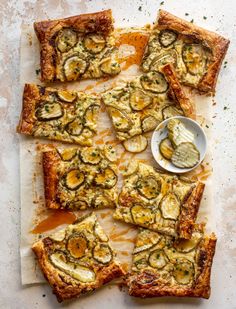 a pizza with zucchini, cheese and sauce on it sitting on top of a cutting board