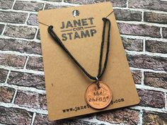 a necklace with a penny on it sitting on top of a piece of brown paper