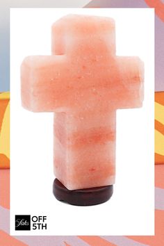 a cross made out of soap sitting on top of a wooden stand in front of a colorful background