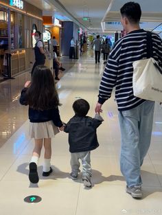 a man and two children are walking down the hall