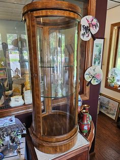 an antique display case with glass doors in a room filled with other antiques and decor