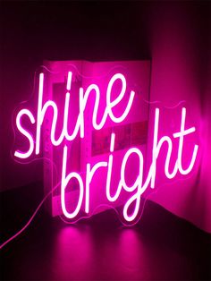 a pink neon sign that says shine bright on the side of a wall in a dark room