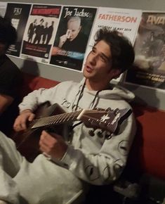 two men sitting on a couch playing guitars