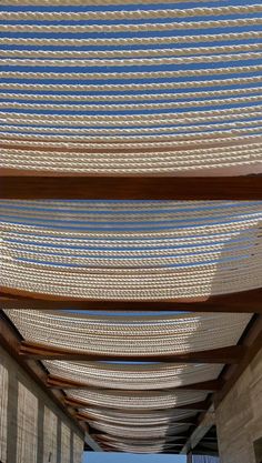 the underside of a wooden structure with ropes hanging from it's sides and blue sky in the background