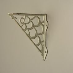 a metal triangle shaped object hanging on the side of a wall with an intricate design