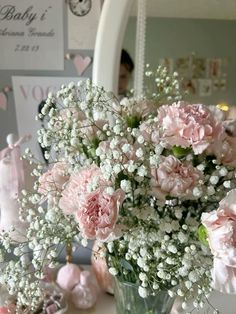 a vase filled with lots of pink flowers on top of a table next to a mirror