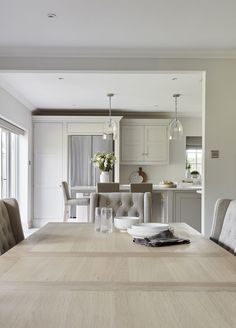 a dining room table and chairs in front of an open kitchen