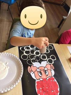 a child is sitting at a table with a paper plate in front of him and a smiley face