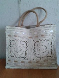 a white crocheted bag sitting on top of a wooden table next to a wall