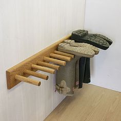 there is a wooden rack with shoes hanging on the wall next to a white wall