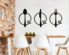 three forks and spoons are hanging on the wall above a dining room table with white chairs